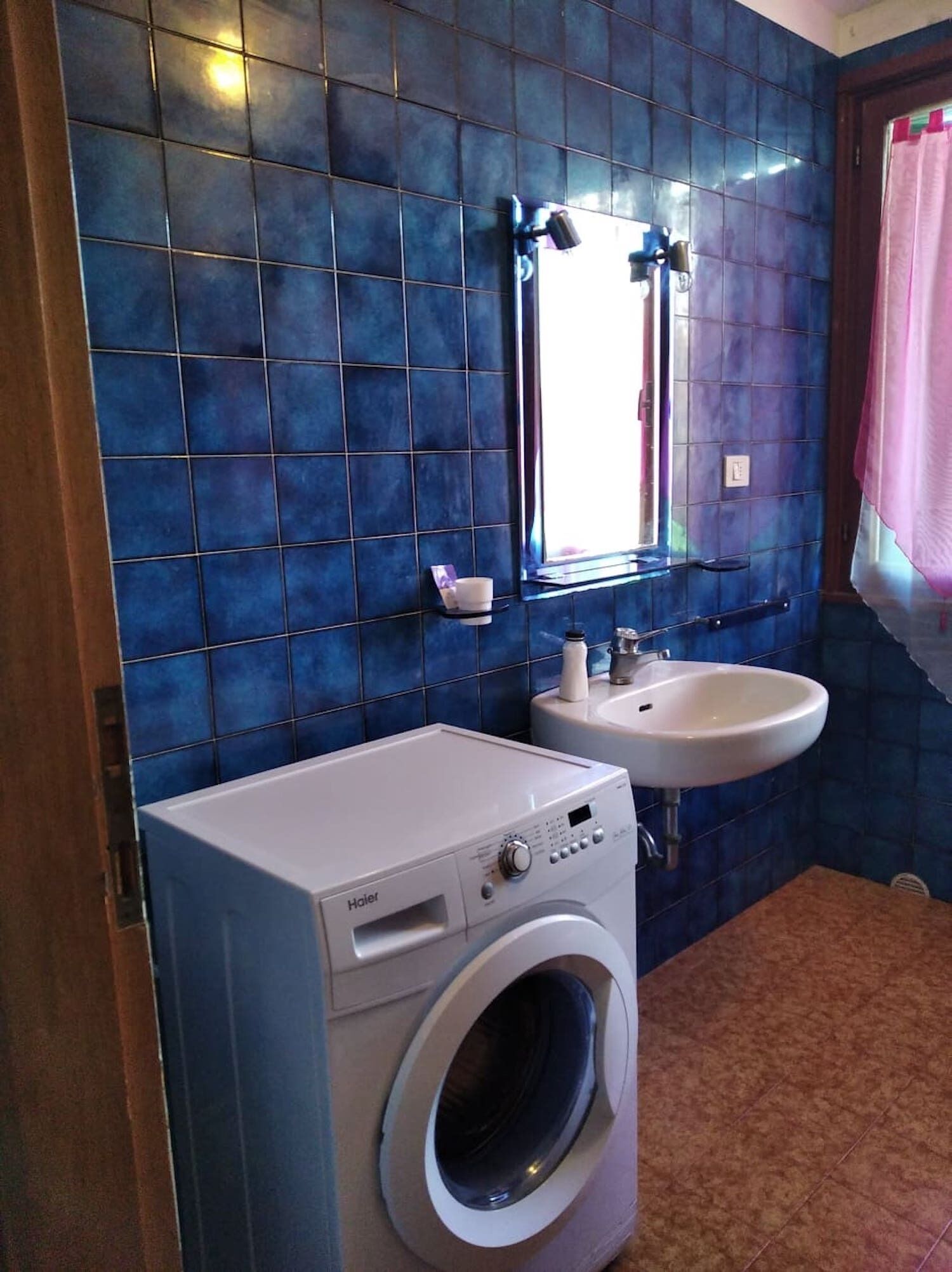 Un baño pequeño con lavadora, lavamanos y espejo.
