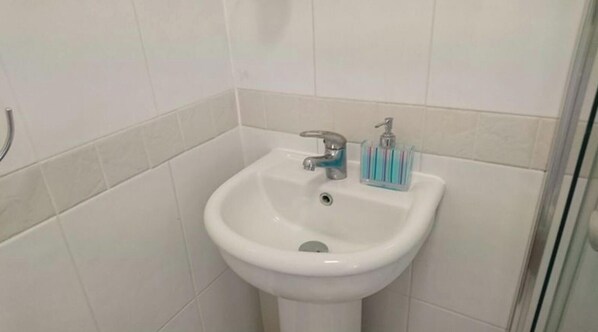 A bathroom with a white pedestal sink, a faucet, and a soap dispenser. - Room-en Suite Shower Room Double Room wi (Hayes)
