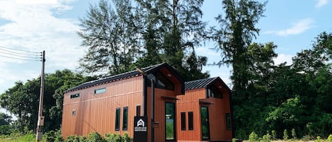 A modern wooden cabin with a sloped roof, large windows, and a small porch.