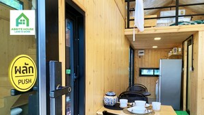 A compact wooden room with a dining table, chairs, a small kitchen area, and a sleeping loft. - 2 Tiny Houses on Koh Lanta Only 2 Minutes Walk to the Beach (Ko Lanta)