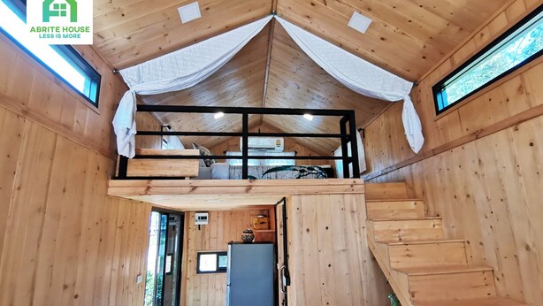 A wooden cabin interior with a loft bedroom, a kitchen area, and a staircase. - 2 Tiny Houses on Koh Lanta Only 2 Minutes Walk to the Beach (Ko Lanta)