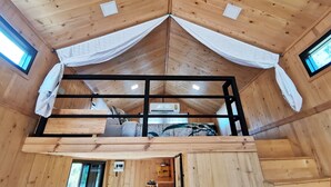 A cozy cabin interior with a loft bed, wooden walls, and a small balcony. - 2 Tiny Houses on Koh Lanta Only 2 Minutes Walk to the Beach (Ko Lanta)