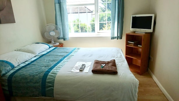 Habitación de hotel con cama, televisor, ventilador y ventana con cortinas.