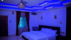 Un dormitorio con cama, cortinas, lámpara de techo y aire acondicionado instalado en la pared.