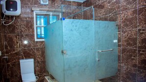 Un baño con ducha de mampara de vidrio, inodoro blanco y pared con azulejos de mármol.