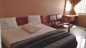 Ein Hotelzimmer mit Bett, Schreibtisch, Stuhl und einem fenster mit Vorhängen.