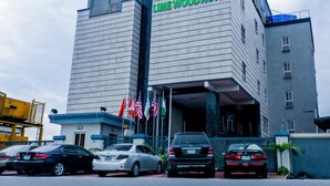 A hotel with a prominent sign reading 'LIME WOOD HOTEL' and multiple flags in front. - Room-limewood Hotel - Guest Room (Port Harcourt)