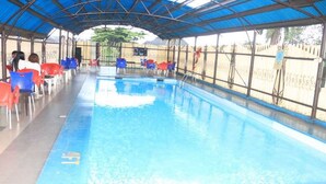 An indoor swimming pool with blue water, surrounded by red and blue chairs, under a blue roof. - Room-the Golf Prince Hotel-guest Room (Port Harcourt)