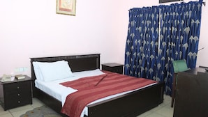 A bedroom with a bed, nightstands, a desk, a chair, a television, and curtains. - Room-the Golf Prince Hotel-guest Room (Port Harcourt)