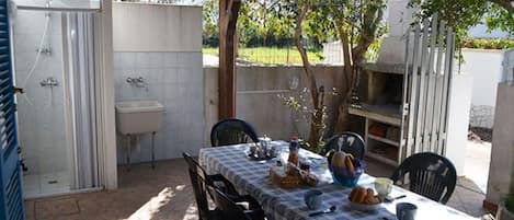 Une terrasse extérieure avec une table dressée pour le petit-déjeuner, un évier et un barbecue.