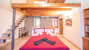 A bedroom with a red bedspread, wooden staircase, stone wall, and a wooden ceiling. - The Amazing Villa Claudia Tuscany Style (Lezzeno)
