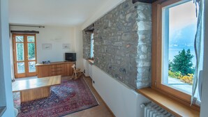 A room with a stone wall, a wooden bench, a radiator, and a window with a view. - The Amazing Villa Claudia Tuscany Style (Lezzeno)