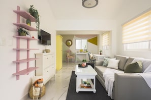 A modern living room with a sofa, coffee table, and a pink shelf unit. - Unwind and Recharge in This Homey Central Retreat (Punta Cana)