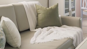 Ein Wohnzimmer mit einem beigefarbenen Sofa, einem weißen Couchtisch und einer Vitrine.