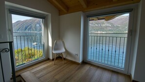 Ein Zimmer mit großen Fenstern, Holzboden und einem weißen Stuhl.