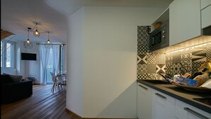 Eine moderne Küche mit gemustertem Rücksprung, Holzboden und einem Essbereich mit Ausblick.
