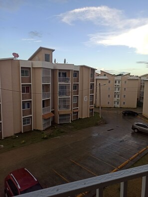 A multi-story residential building with balconies, a parking area, and a satellite dish on the roof.