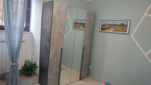 A room with a large wardrobe, a potted plant, and two framed pictures on the wall. - Casa Sara Holiday Home (Spello)