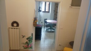 A hallway leading to a dining area with a table and chairs, a radiator, and a wall with a tropical mural. - Casa Sara Holiday Home (Spello)