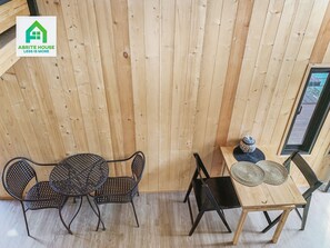 A room with a wooden slatted wall, a round table with chairs, and a small table with decorative items. - Tiny House on Koh Lanta Only 2 Minutes Walk to the Beach (Ko Lanta)