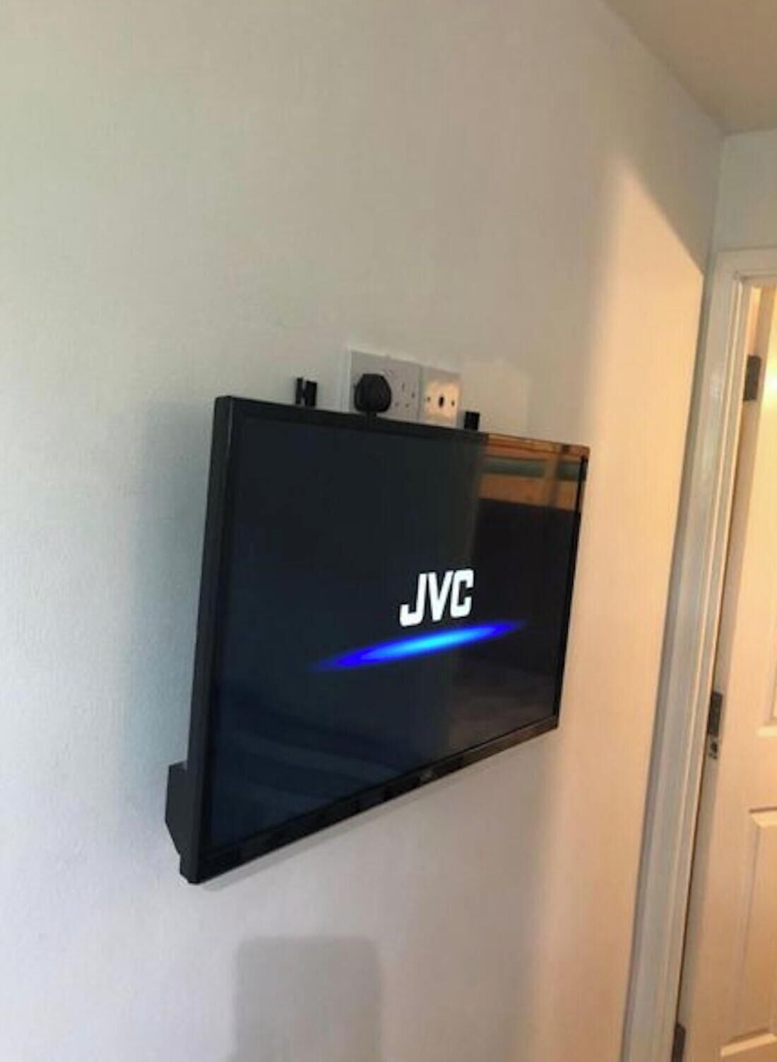 Un televisor de pantalla plana montado en una pared, con la marca 'JVC' a la vista.