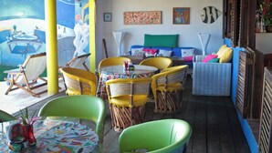 A covered outdoor seating area with wicker chairs and a table, a blue sofa, and a mural on the wall. - Room-small Luxury Hotel, Hideaway Near A (Coyuca de Benitez)