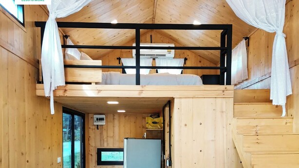 Una cabaña de madera con literas, una kitchenette pequeña y un ventanal.