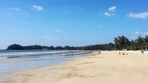 Una playa con cielos despejados, aguas tranquilas y un área boscosa en la distancia.