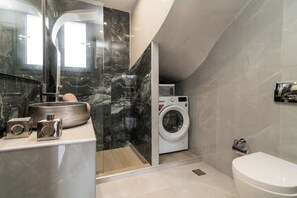 A modern bathroom with a marble sink, a washing machine, and a toilet. - Grande Amore Luxury Villa (Zakynthos)