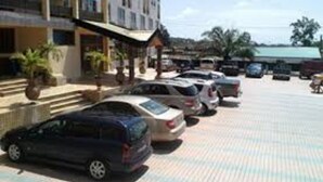 A hotel with multiple floors, a covered entrance, and a parking lot with several cars. - Luxurious Sunset Hotel in Kumasi (Kumasi)