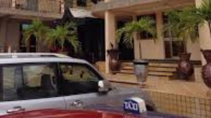 A multi-story building with balconies, a car in front, and potted plants. - Luxurious Sunset Hotel in Kumasi (Kumasi)