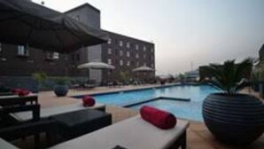 A hotel pool area with lounge chairs and umbrellas. - Luxurious Sunset Hotel in Kumasi (Kumasi)