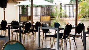 Un espace extérieur aménagé avec des tables et des chaises, un parasol vert et une clôture en métal.