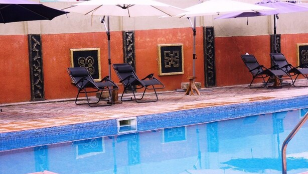 Une piscine avec des chaises longues et des parasols.