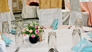 Une table de banquet dressée avec de beaux verres, un vase rempli de fleurs roses et des serviettes soigneusement pliées.