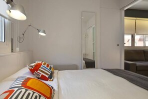 Ein Hotelzimmer mit Bett, Schreibtisch, Stuhl, Lampe und Fenster.