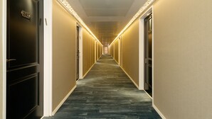 A long, narrow hotel corridor with a carpeted floor and doors on both sides. - Shefayim Hotel (Hod HaSharon)