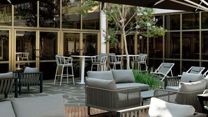 An outdoor seating area with wicker furniture and a stone floor. - Shefayim Hotel (Hod HaSharon)