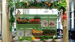 A food display counter with fresh produce and labeled signs for items like carrots, sweet peas, and vine-ripe tomatoes. - Shefayim Hotel (Hod HaSharon)