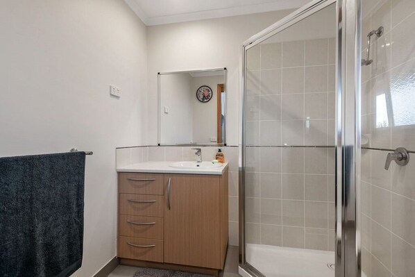 A bathroom with a shower, a sink, and a mirror.