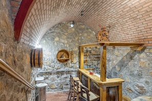 A stone-walled bar area with wooden furniture, a small statue, and a rustic ambiance. - Vineyard Homestead Vrtin (Crnomelj)
