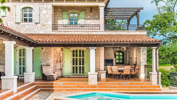 A two-story stone building with a covered patio, outdoor seating, and a swimming pool. - Luxury 4-BR Villa with Pool, Ensuite Sauna, and Stunning Sea & Forest Views (Višnjan)