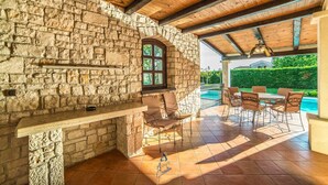 A stone-walled outdoor patio with a pool, wooden ceiling beams, and outdoor furniture. - Luxury 4-BR Villa with Pool, Ensuite Sauna, and Stunning Sea & Forest Views (Višnjan)