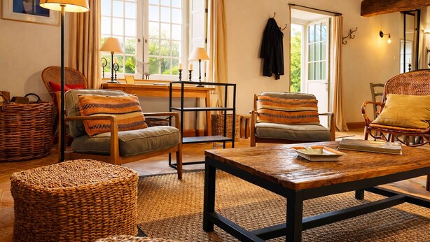 A cozy living room with wicker furniture, a wooden coffee table, and a dining table.