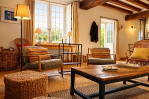 Una sala de estar acogedora con muebles de mimbre, una mesa de centro de madera y una mesa de comedor.