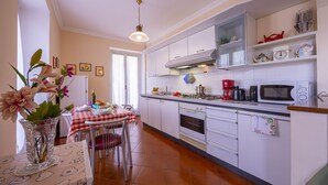 A kitchen with white cabinets, a dining table with a checkered tablecloth, and a vase with flowers.