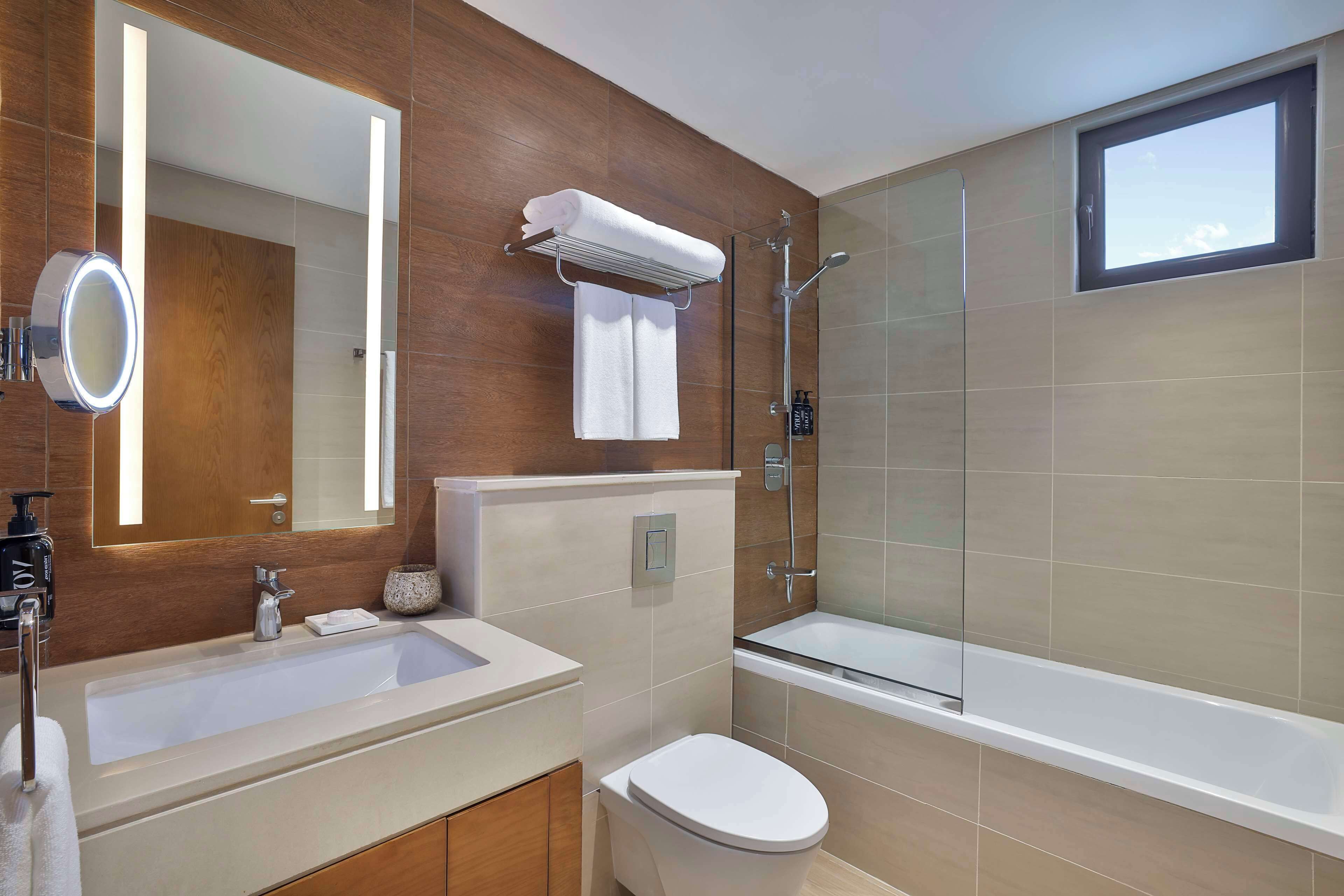 Un baño moderno con un espejo grande, una bañera y una ducha.