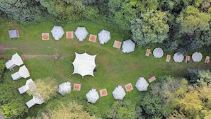 Eine Luftaufnahme eines Campingplatzes mit sechseckigen Zelten, die in einem Kreis um einen zentralen, offenen Bereich angeordnet sind.