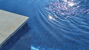 Vista clara de una piscina con escalones de cerámica que bajan al agua.