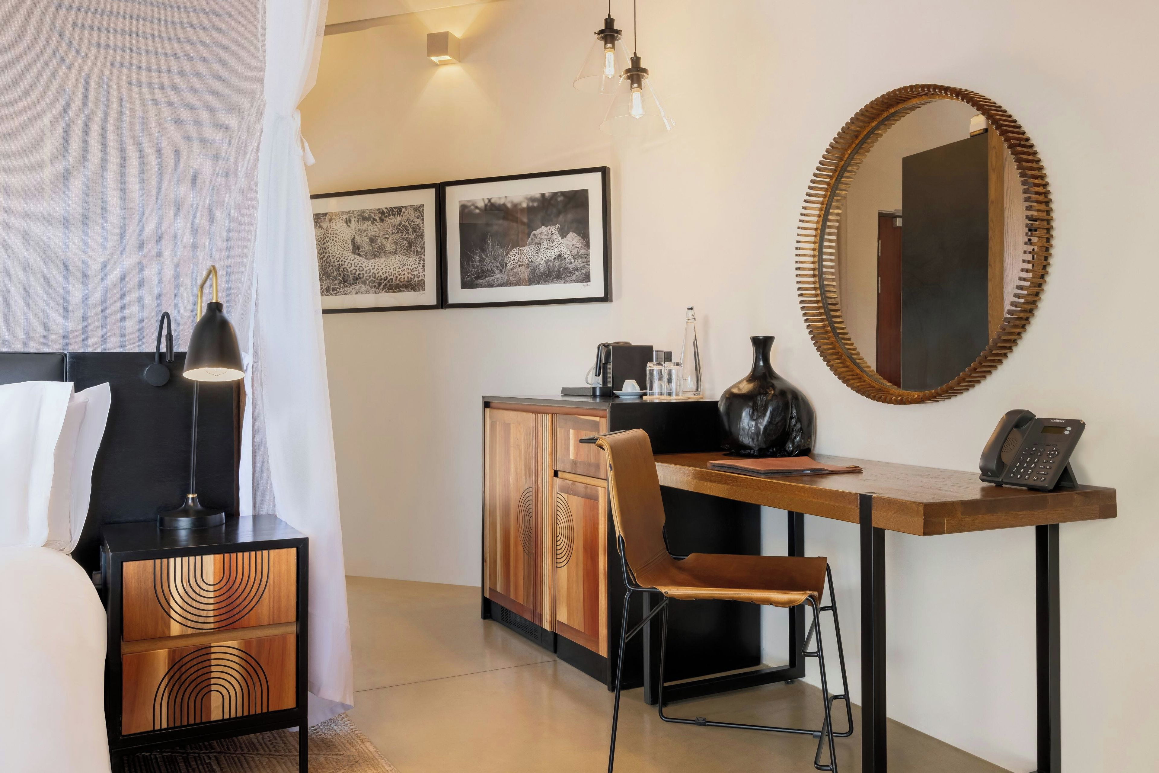Une chambre d’hôtel avec un lit, un bureau, une chaise, un miroir et deux tableaux encadrés au mur.